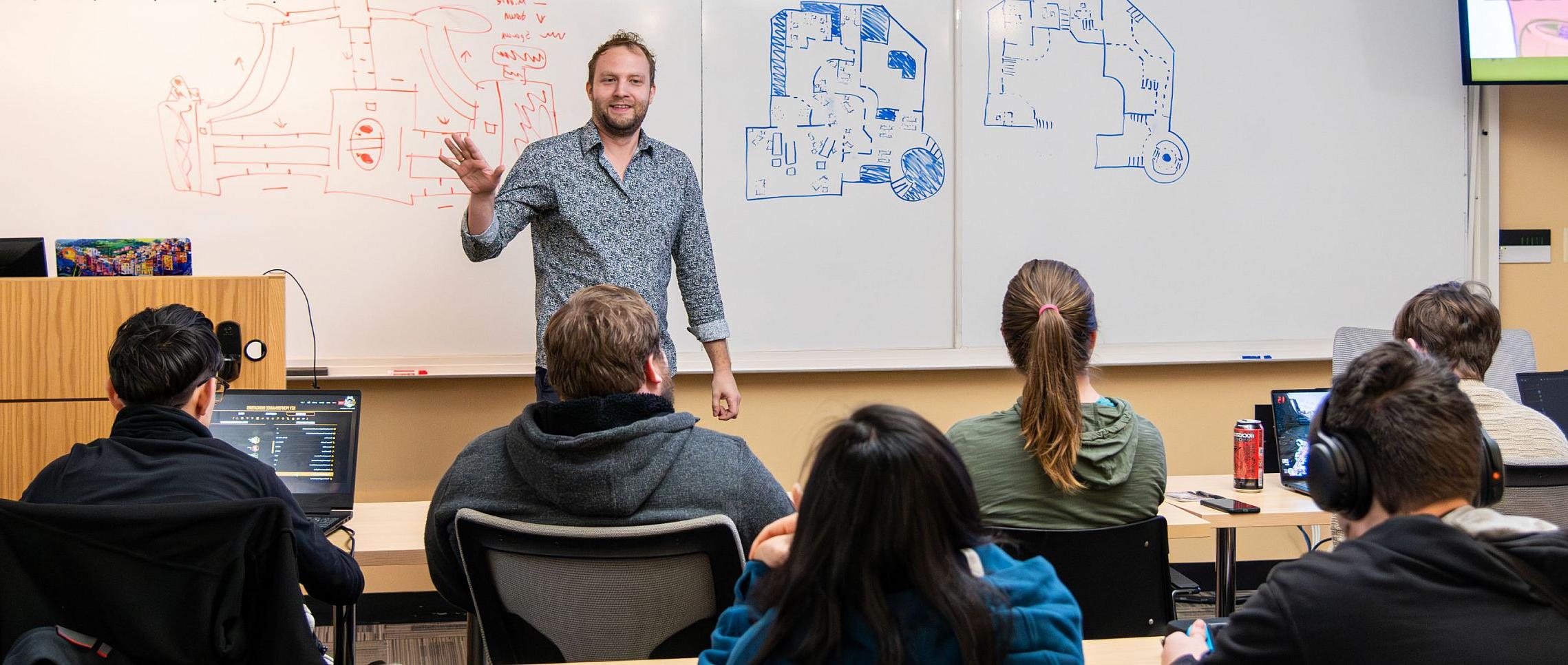 A computer science professor in front of a classroom of students.